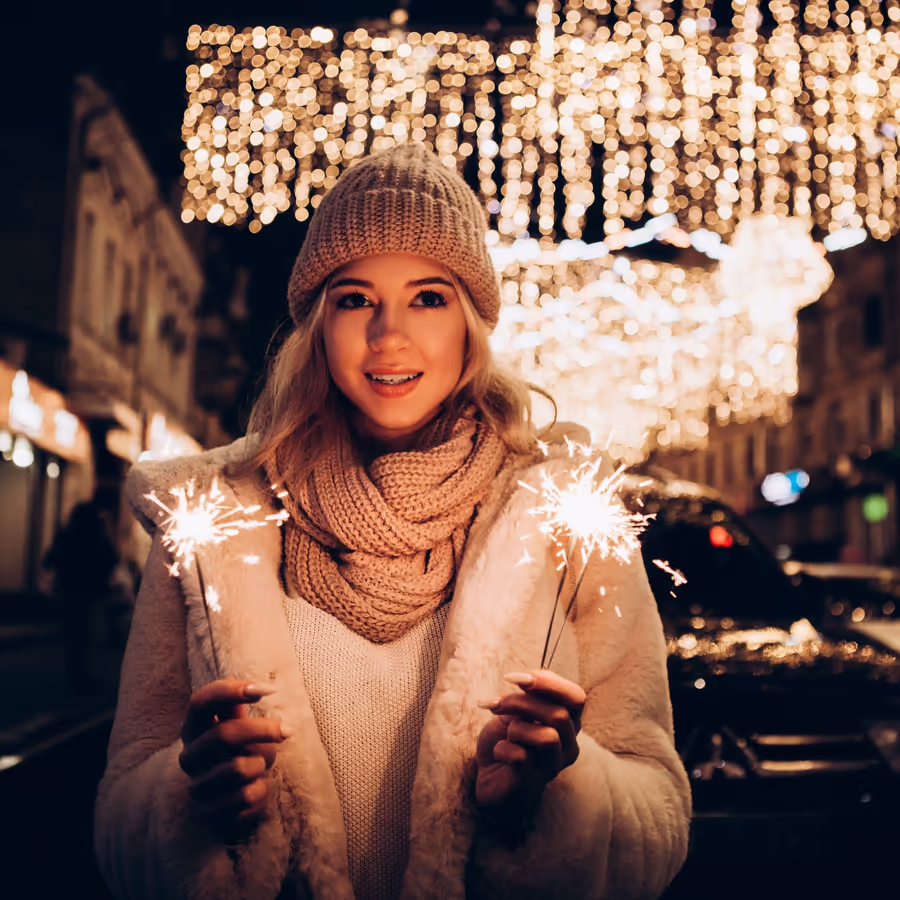 Радостная девушка держит бенгальские огни в зимнем городе