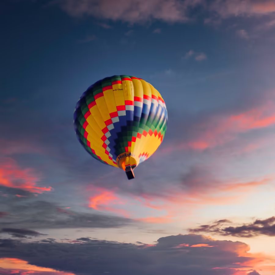 Яркий воздушный шар парит в небе на фоне красивого заката