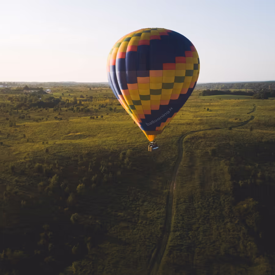 Красочный воздушный шар парит над зелеными полями и лесами