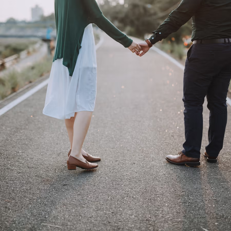 Влюбленная пара прогуливается по дороге держась за руки