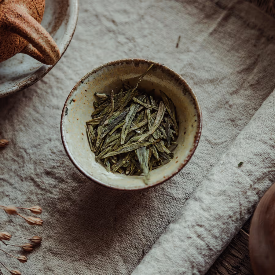 Чашка ароматного зеленого чая Лун Цзин известного своим нежным вкусом и формой листьев