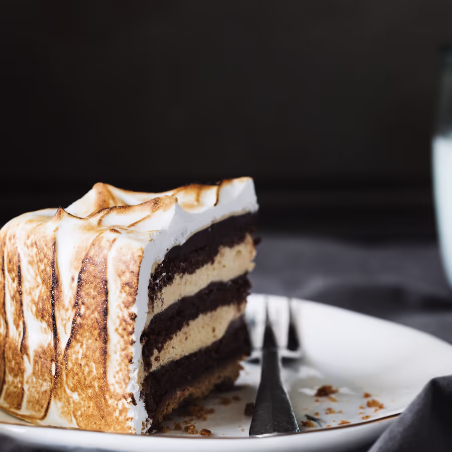 Аппетитный кусочек шоколадного торта покрытый пышной поджаренной меренгой