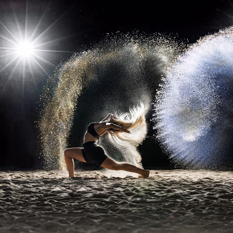 Грациозная танцовщица в момент движения окруженная облаком цветной пыли