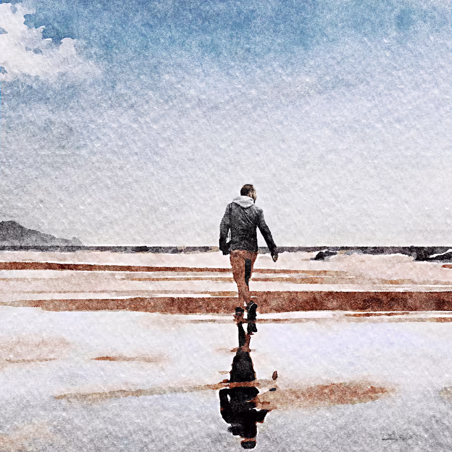 Мужчина идет по мокрому песчаному пляжу в одиночестве