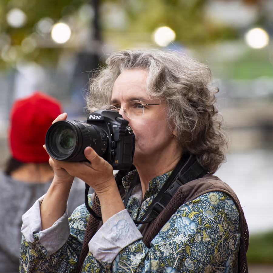 Мужчина с камерой Nikon делает снимок на улице