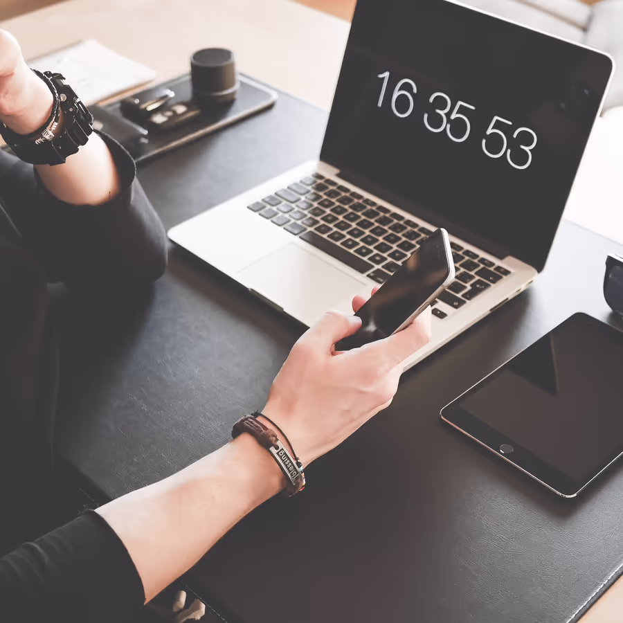 Человек работает за ноутбуком используя смартфон и планшет