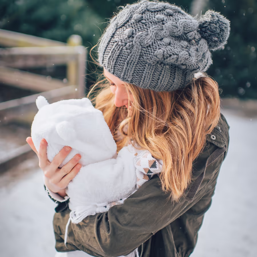 Нежная мама держит новорожденного ребенка в зимний день