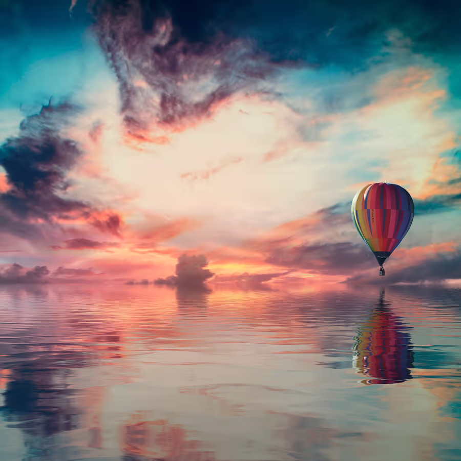 Яркий воздушный шар парит над спокойной водной гладью в лучах заката