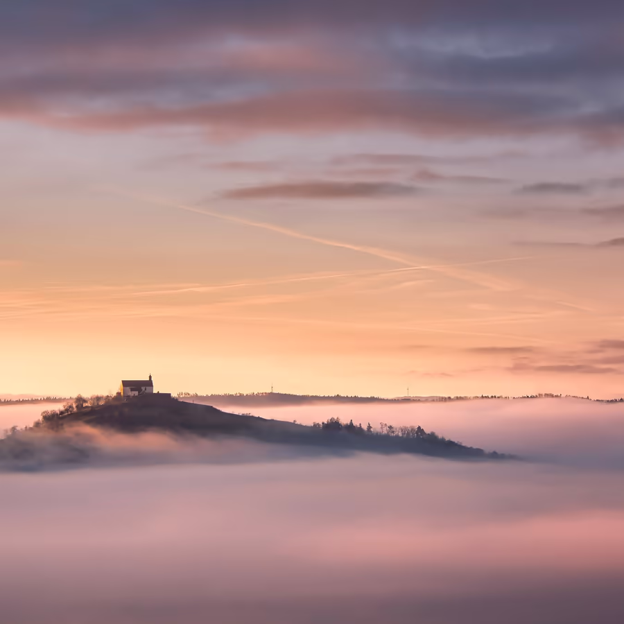 Уединенный замок возвышается над морем облаков на фоне рассветного неба