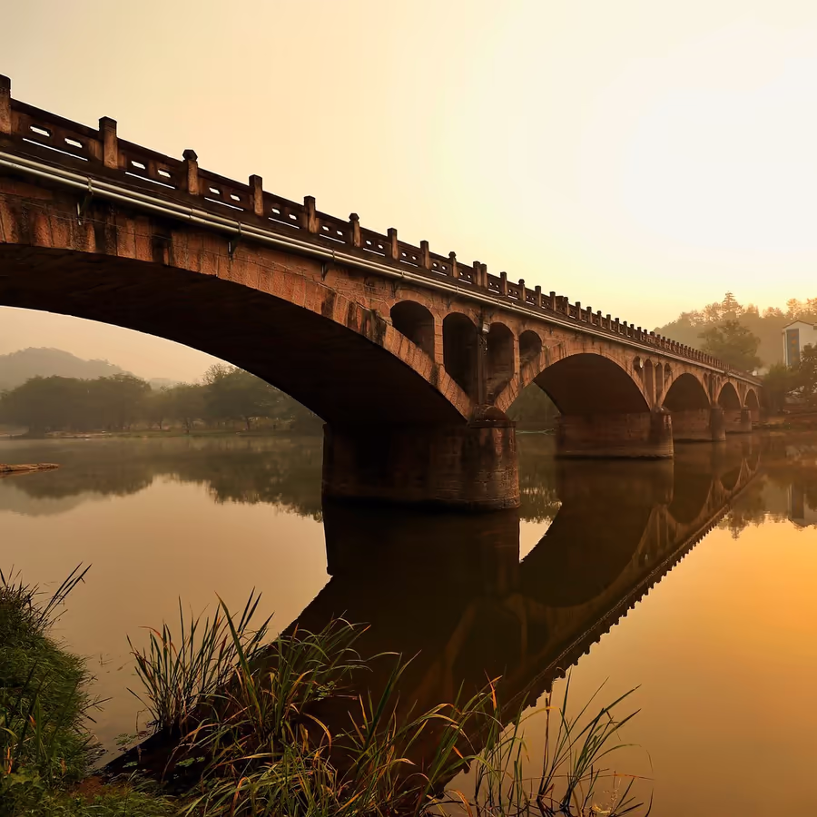 Красивый старый мост отражается в спокойной воде на рассвете