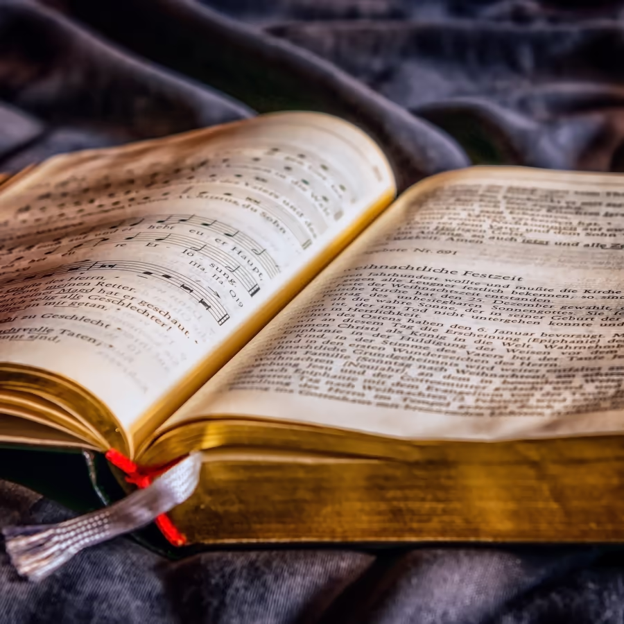 Раскрытая старинная книга с пожелтевшими страницами заполненными музыкальными нотами и текстом