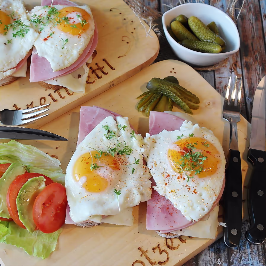 Аппетитные бутерброды с жареным яйцом ветчиной свежими овощами и соленьями