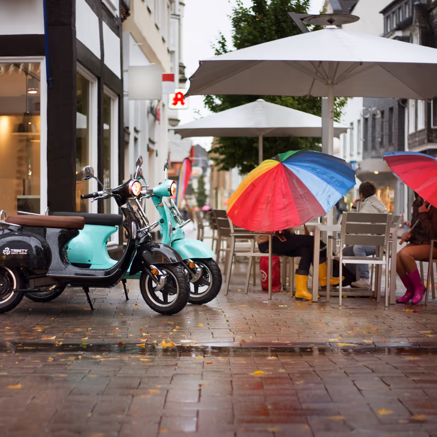 Уютное кафе в дождливый день Электроскутеры и яркие зонтики