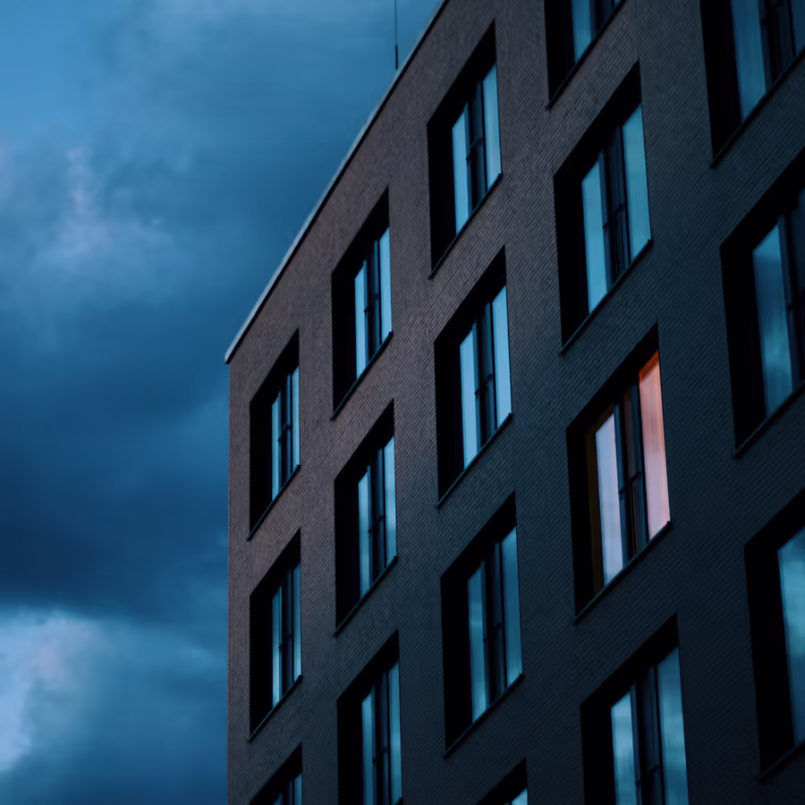 Темный фасад современного здания с освещенным окном