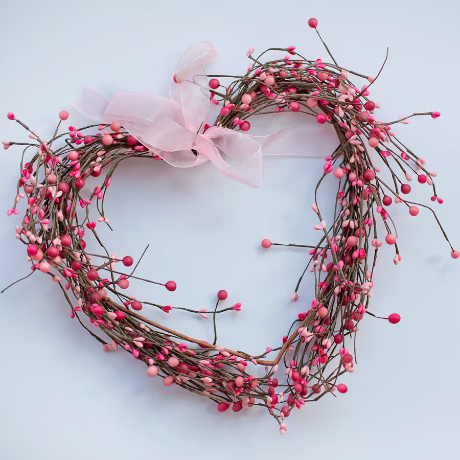 Декоративный венок в форме сердца украшенный розовыми ягодами и атласным бантом
