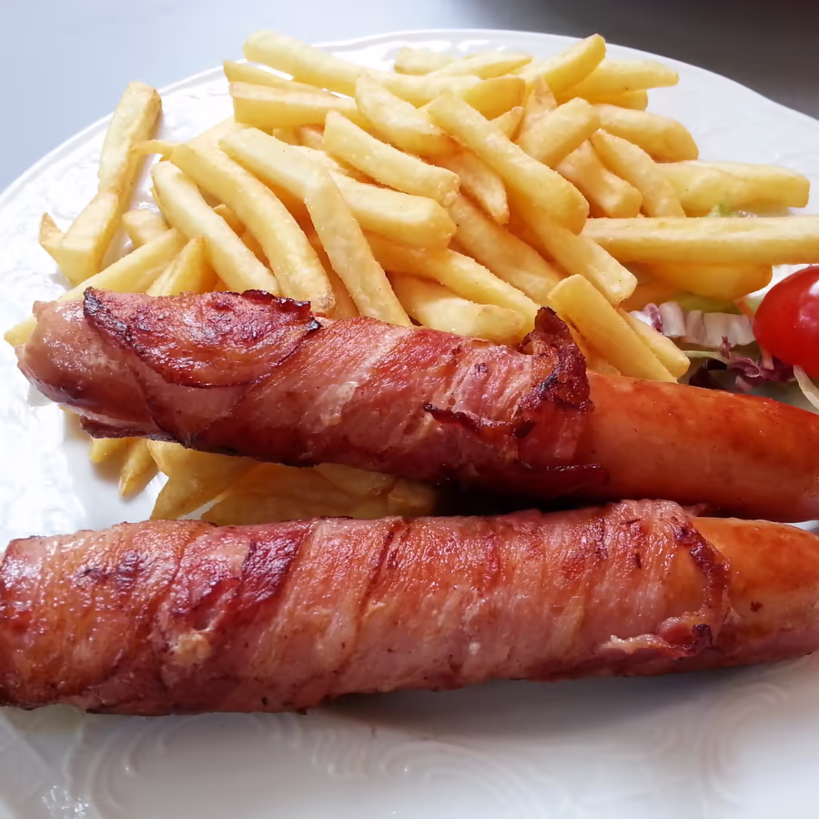 Аппетитные сосиски обернутые в хрустящий бекон подаются с золотистым картофелем фри