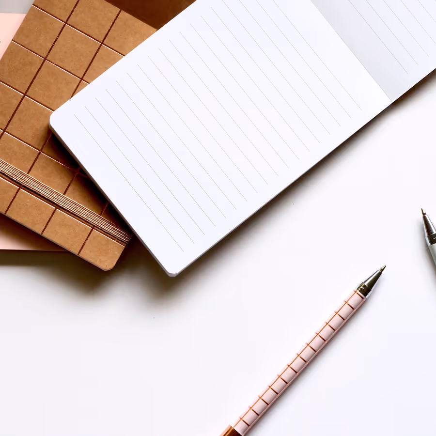 Пустой блокнот и стильная ручка на белом фоне