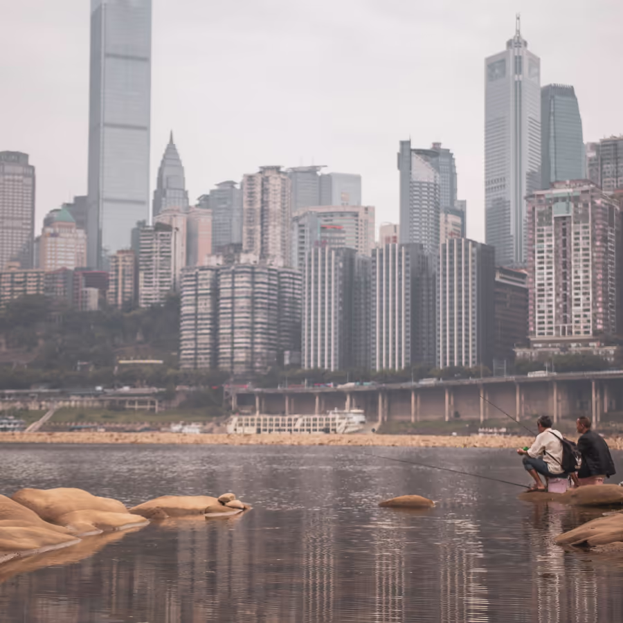 Рыбаки на берегу реки с видом на небоскребы