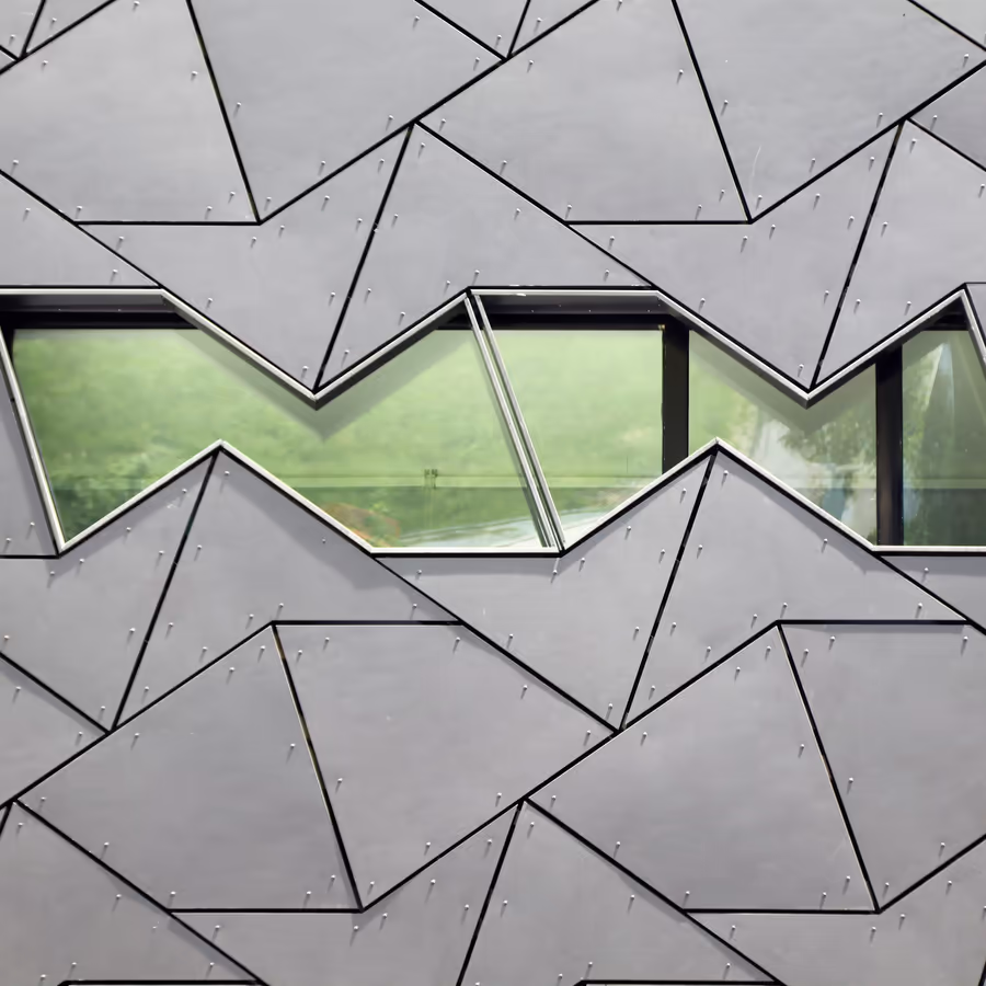 Фрагмент фасада современного здания с необычной геометрической формой и окнами