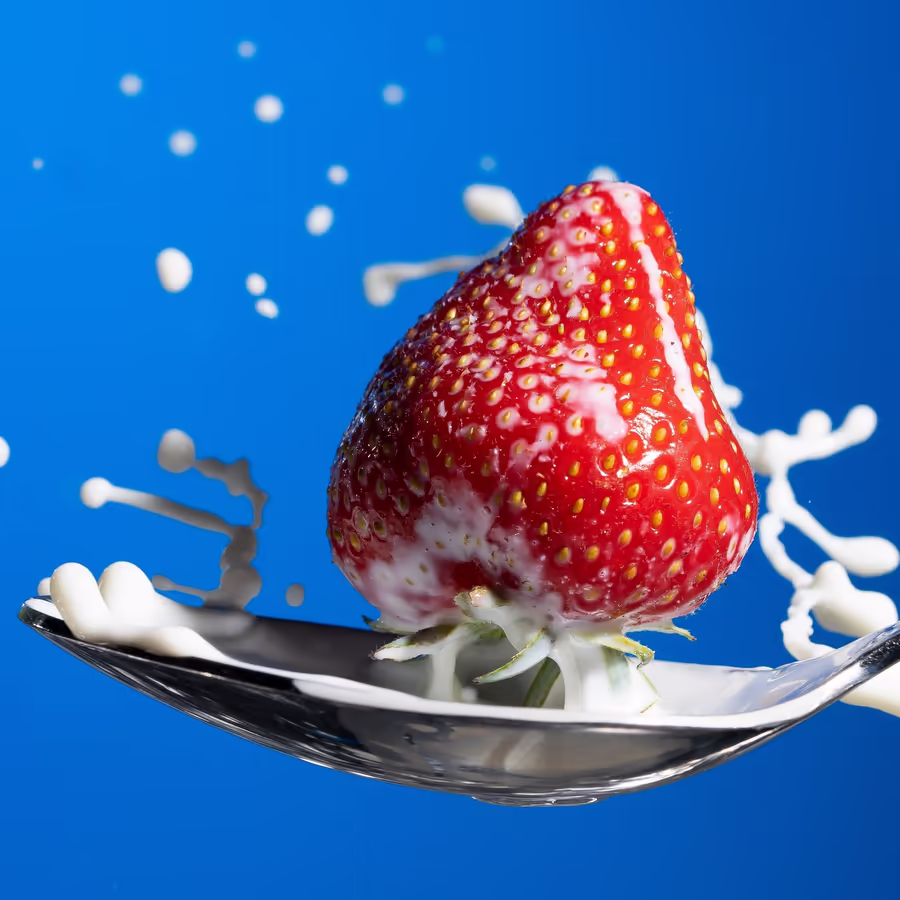 Свежая клубника падает в молоко создавая эффектный всплеск