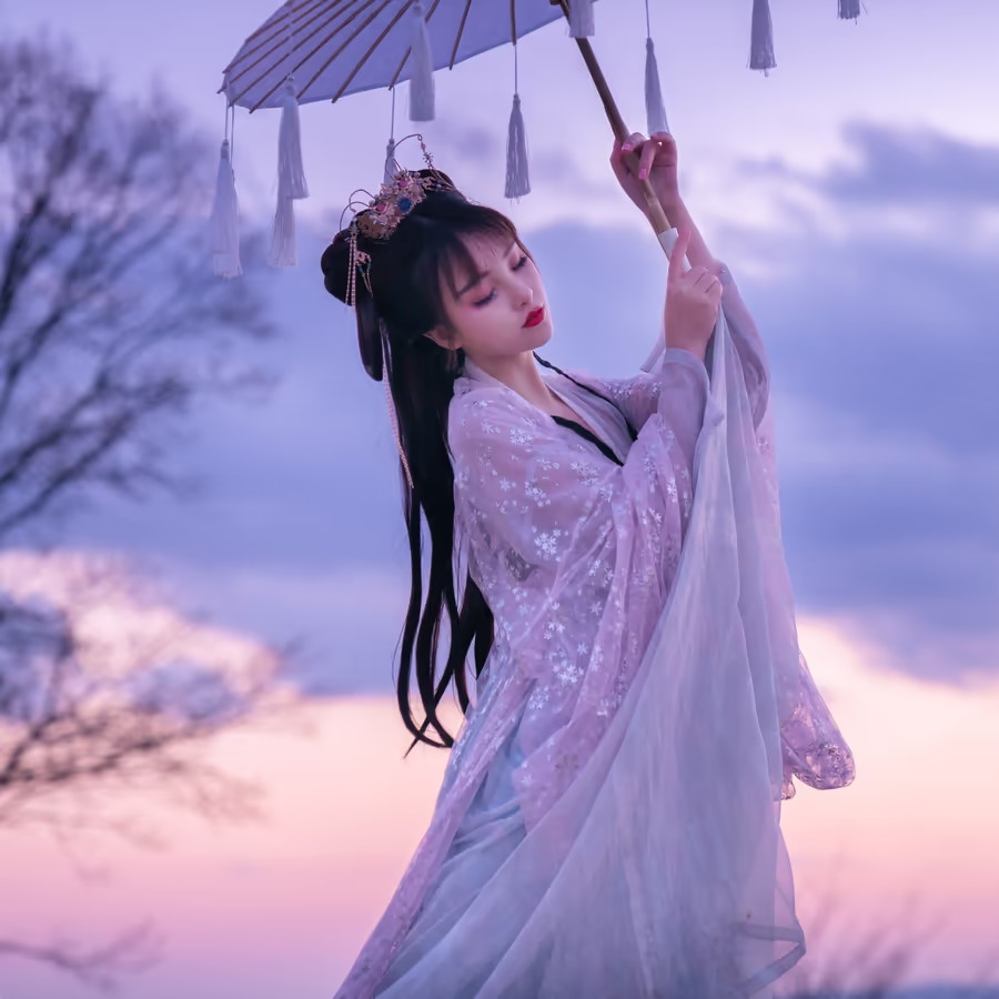 Изящная девушка в традиционном китайском платье ханьфу держащая белый зонт на фоне заката