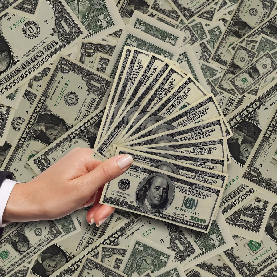 Рука держит веер из долларовых банкнот