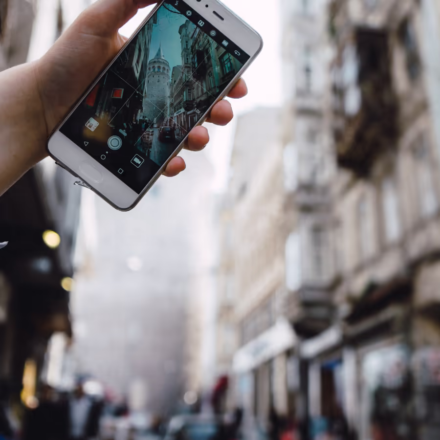 Рука держит телефон фотографируя здание в городе