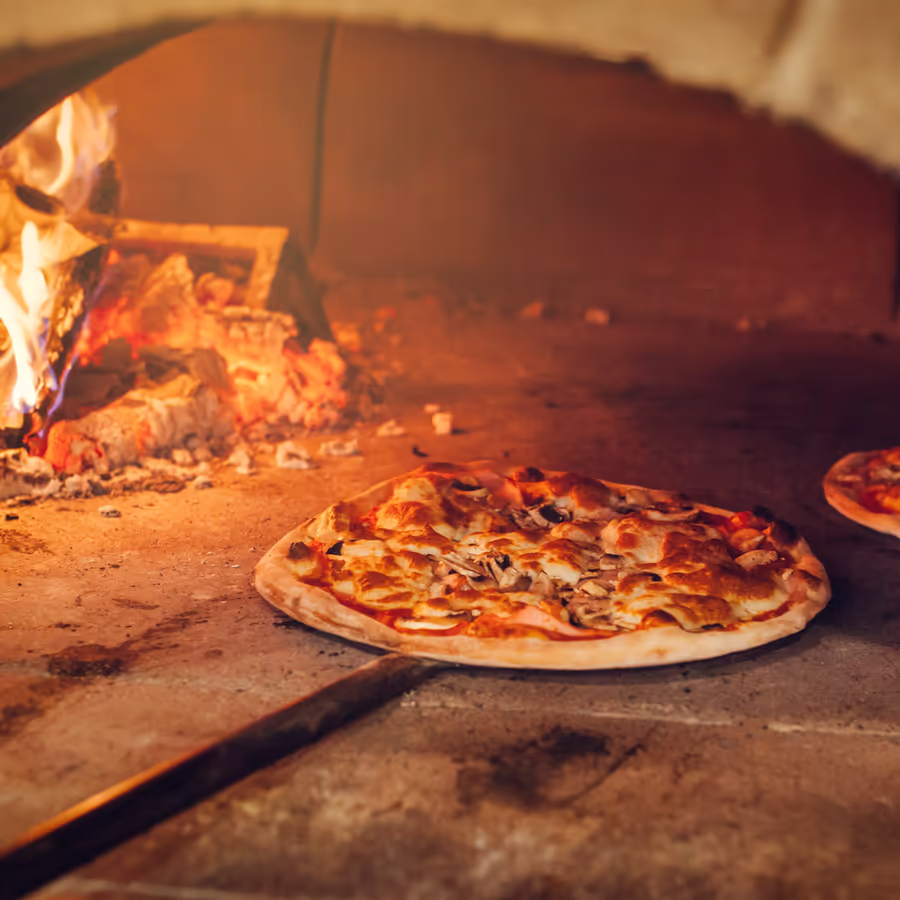 Горячая пицца готовится в традиционной дровяной печи