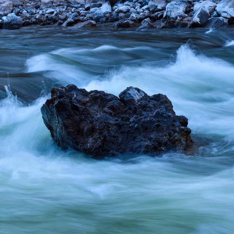 Большой камень окруженный пенящейся водой быстротекущей реки