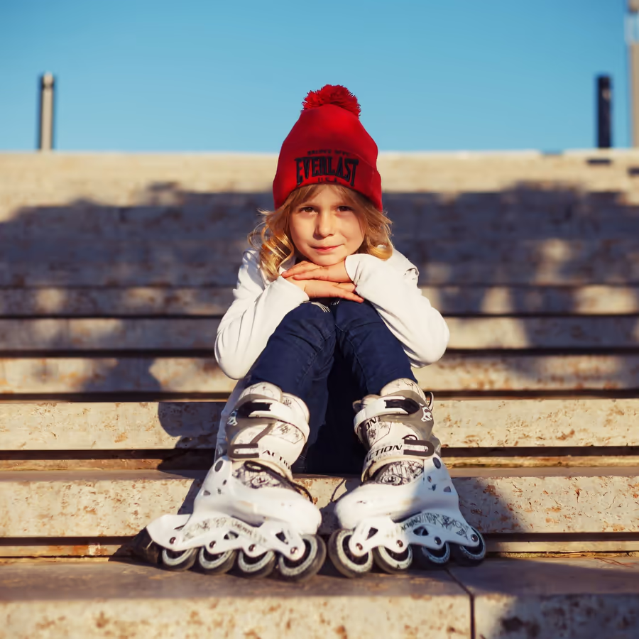 Маленькая девочка отдыхает на ступеньках в роликовых коньках