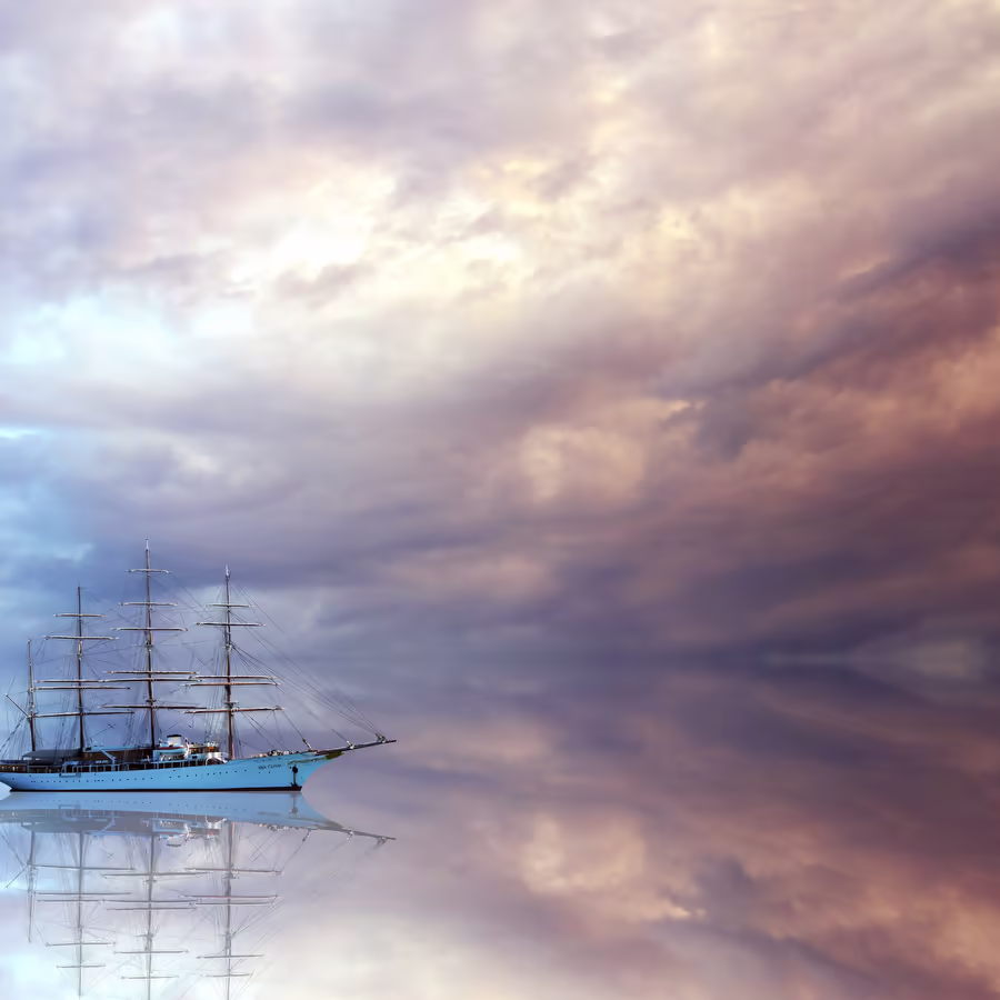 Великолепный парусник под драматическими облаками на фоне заката