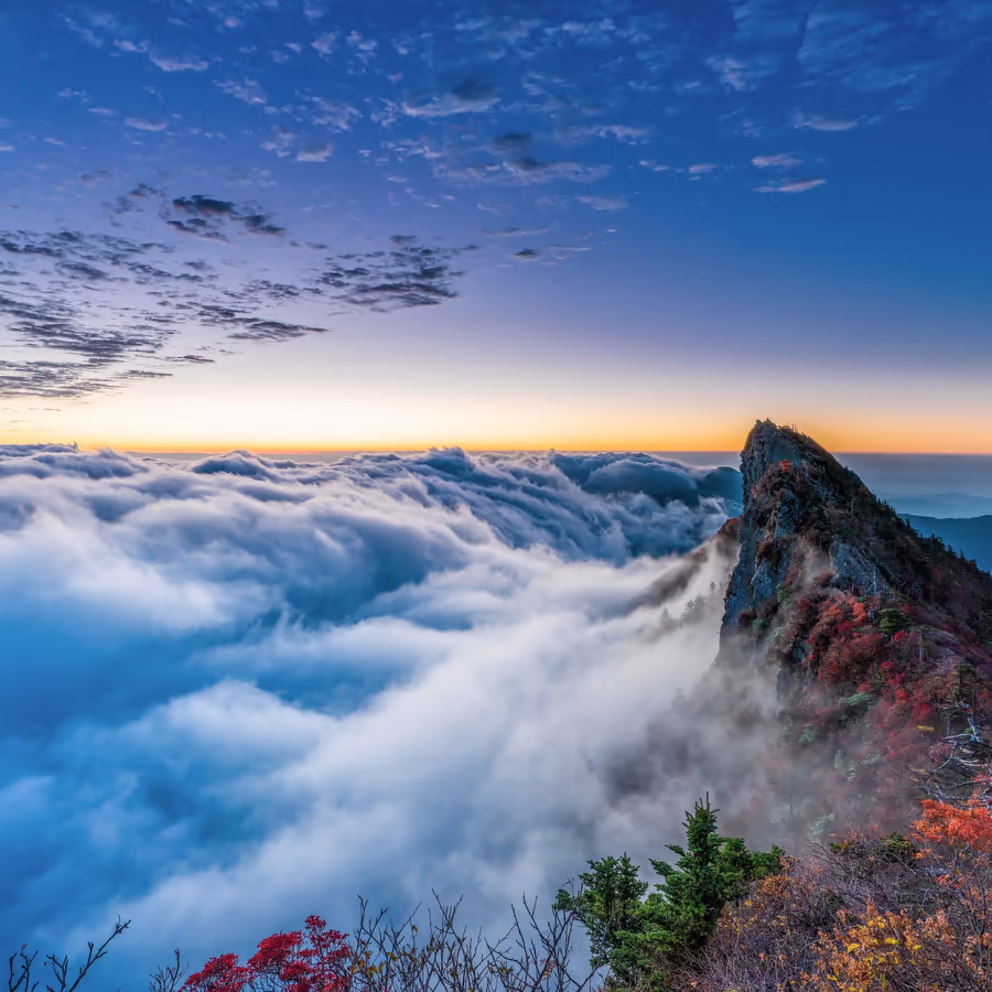 Величественная гора возвышается над морем облаков во время заката