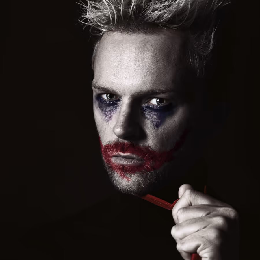 Мужчина с гримом в стиле Джокера выражающий мрачную харизму
