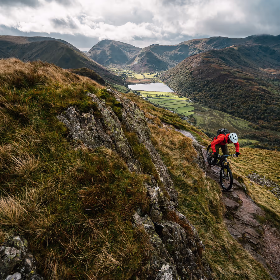 Велосипедист спускается по горной тропе с потрясающим видом