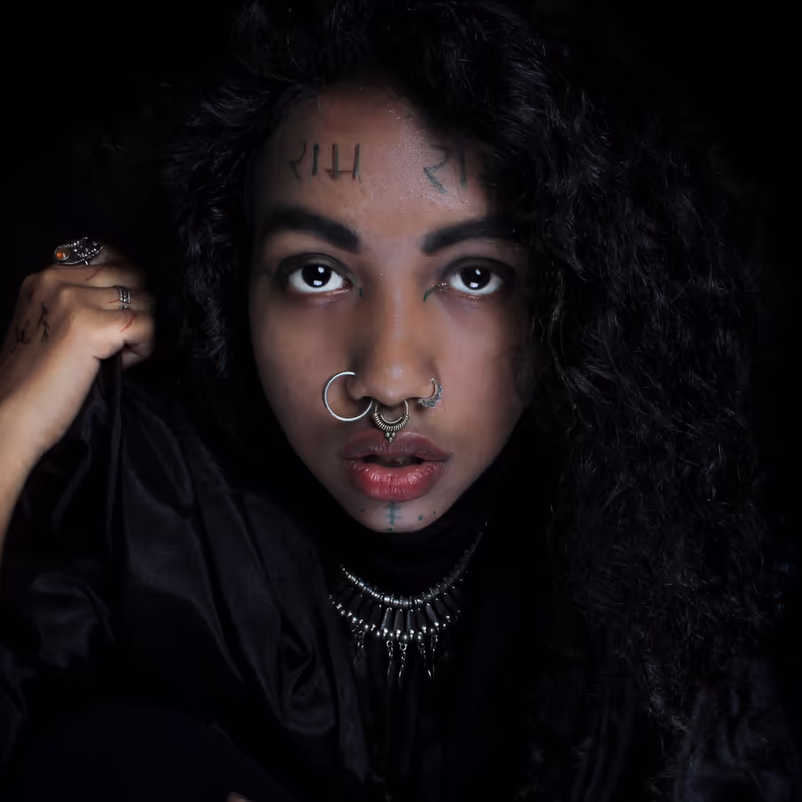 Загадочный портрет человека с темными волосами украшенного рунами и пирсингом