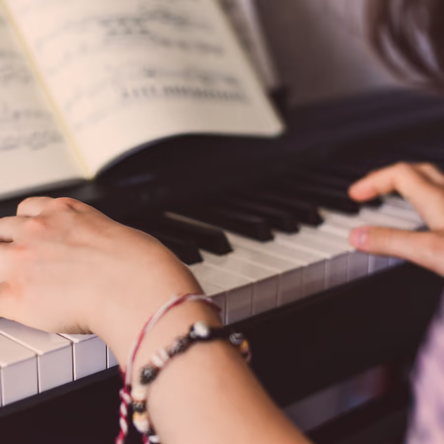 Руки пианиста на клавишах рояля с нотами на пюпитре