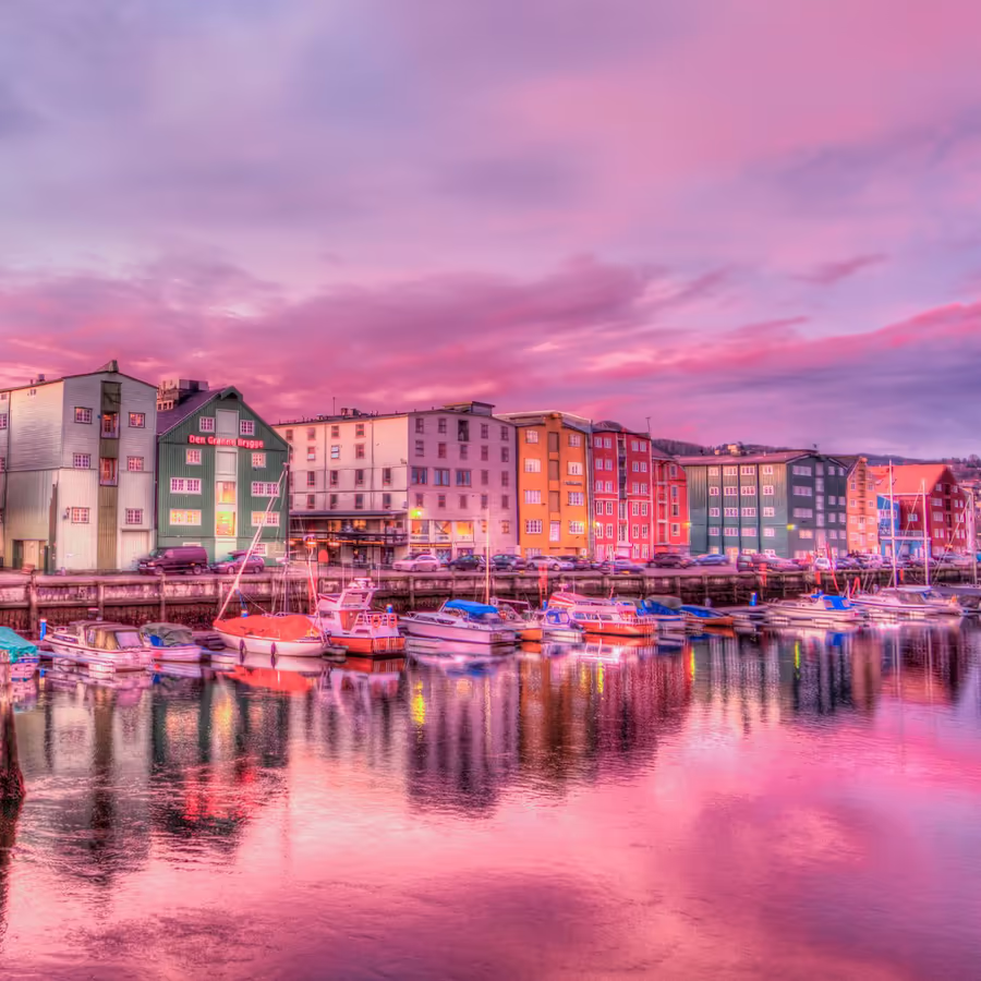 Живописный вид гавани Бергена с разноцветными домами и лодками во время заката