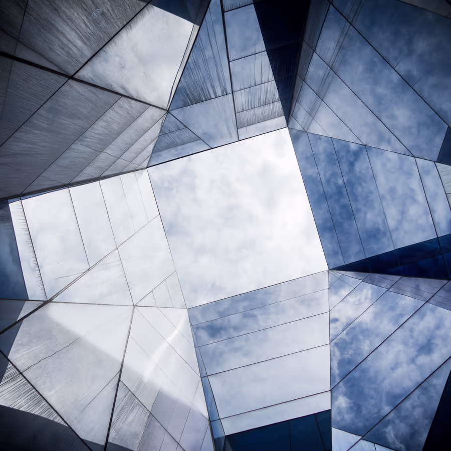 Фрагмент фасада современного здания из стекла с отражением неба