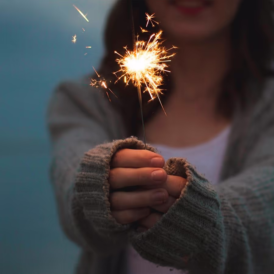 Девушка держит горящий бенгальский огонь