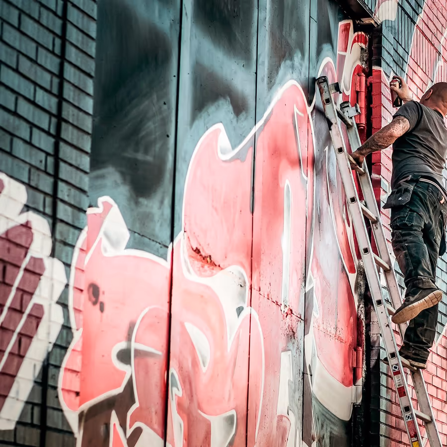 Художник рисует граффити на стене здания