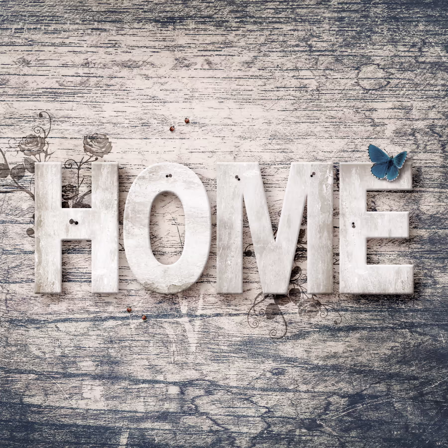 Слово HOME выложено из деревянных букв на фоне состаренного дерева