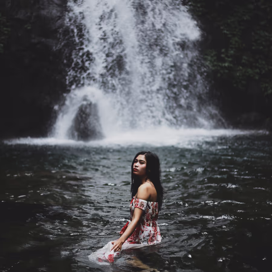 Молодая женщина в реке перед мощным водопадом