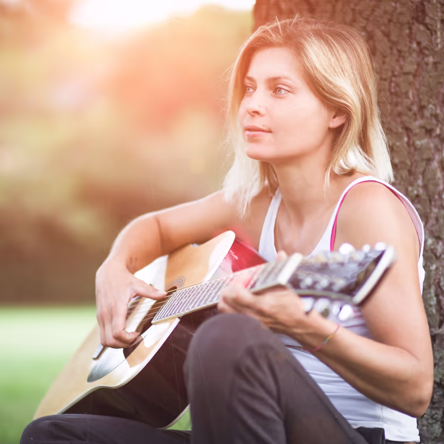 Молодая женщина играет на гитаре в парке